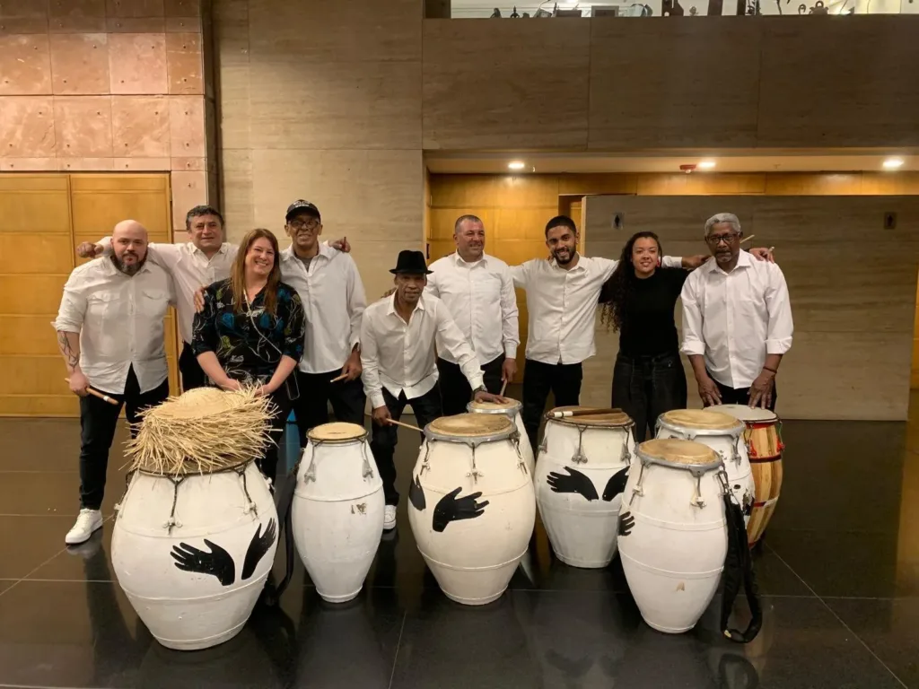 Grupo con camisas blancas posando con los tambores de la Escuela de Candombe.