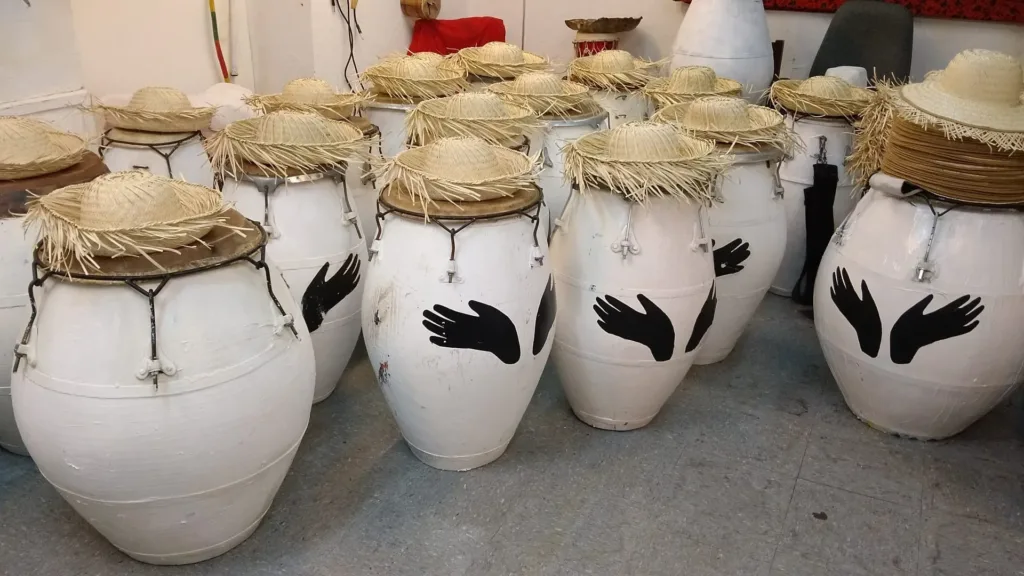 Tambores blancos con las manos de Mundo Afro pintadas y sombreros de paja encima.