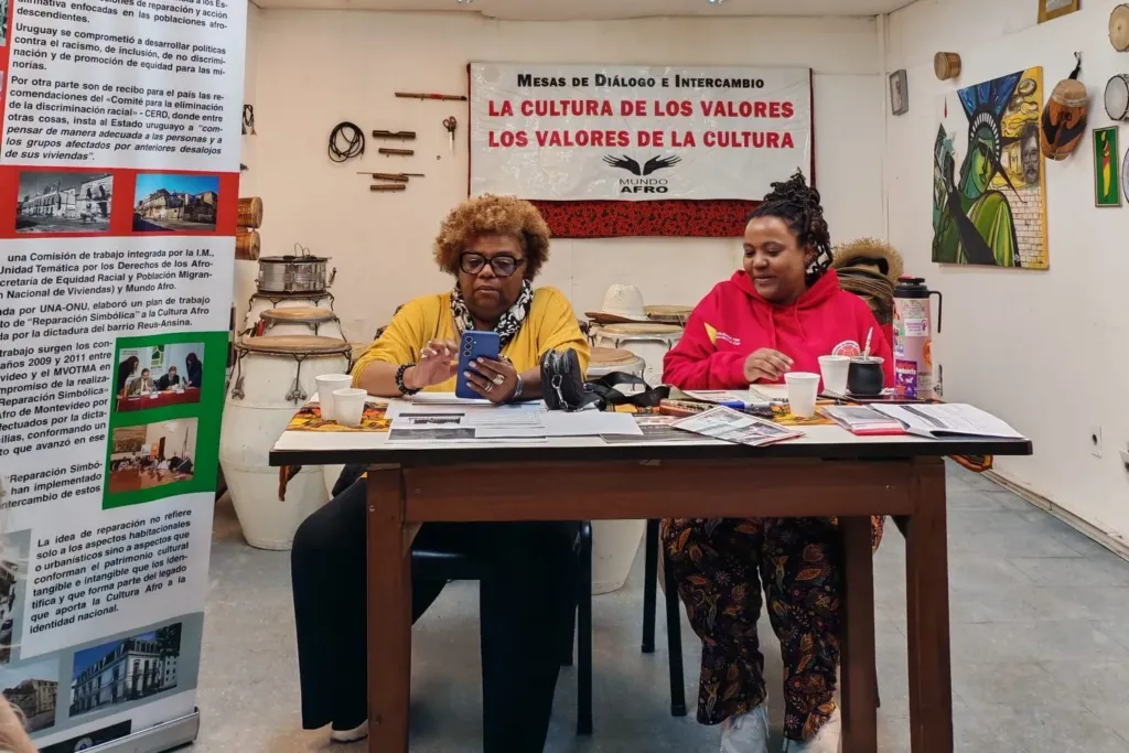 Mesa de Diálogo e Intercambio sobre reparación simbólica, con el panel informativo de fondo.