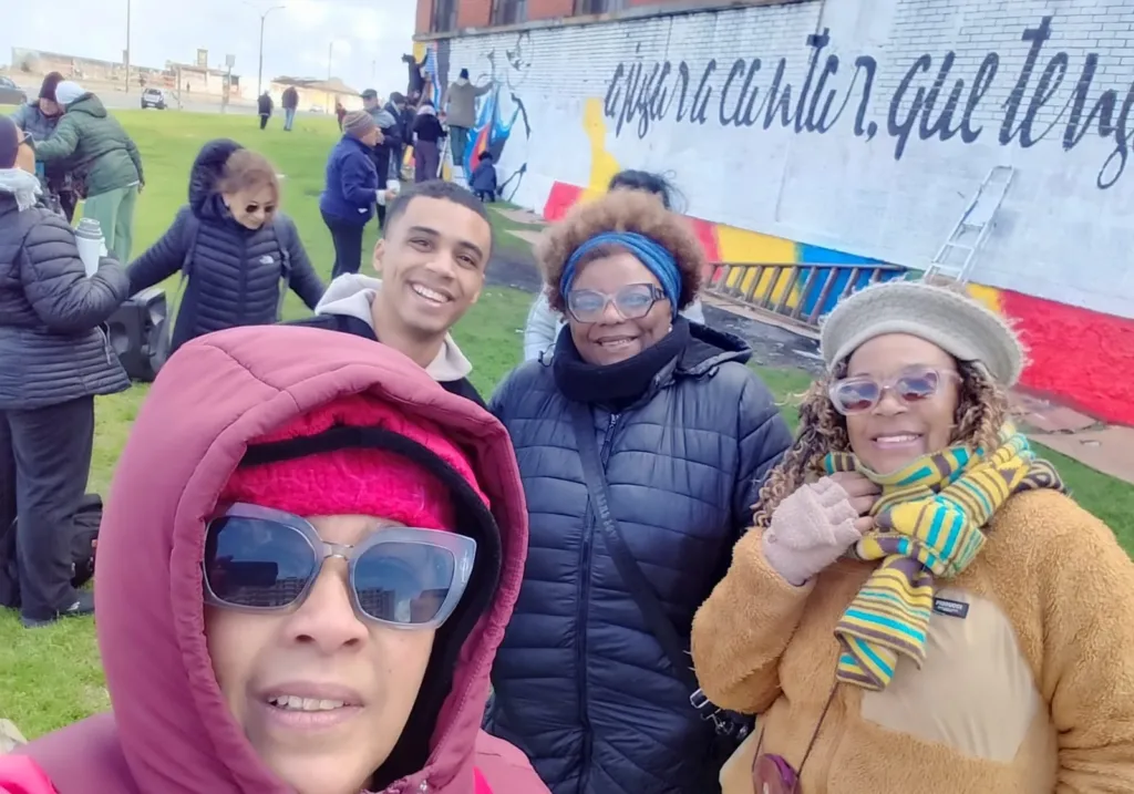 Integrantes de Mundo Afro junto a un mural comunitario en pleno proceso de pintura.