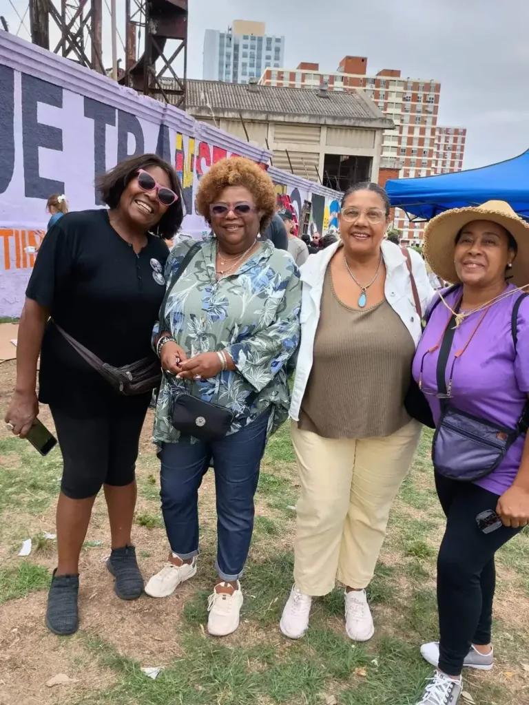 Cuatro mujeres frente a un mural pintado en una jornada comunitaria.